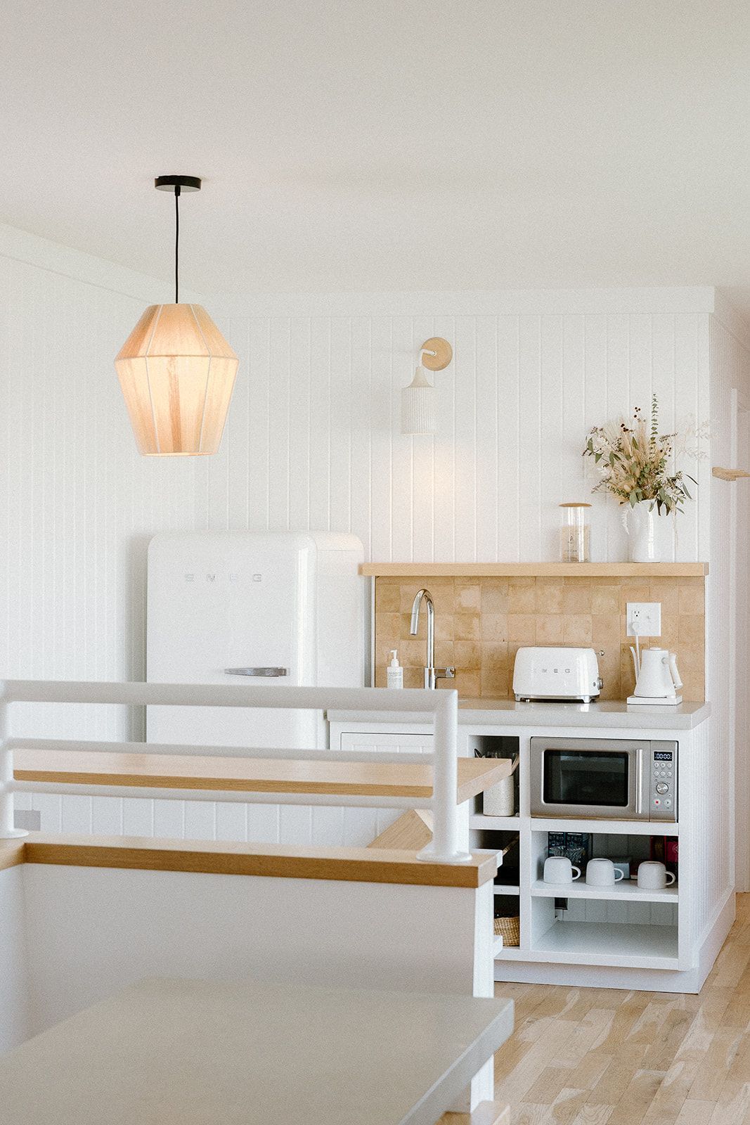 A kitchen with white cabinets , a refrigerator , a toaster oven , and a microwave.