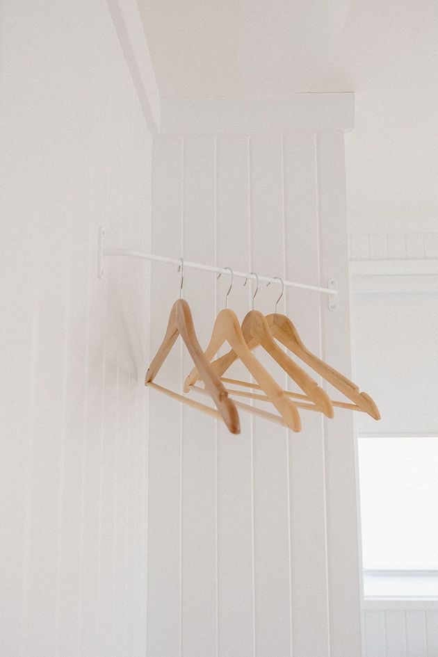 A row of wooden hangers hanging on a white wall.