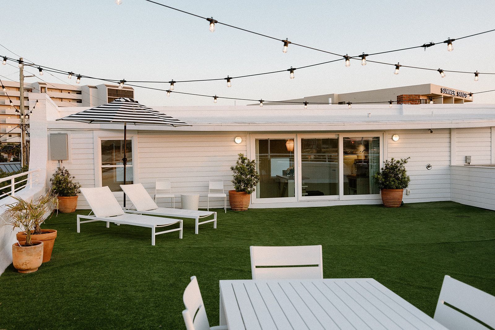 A rooftop patio with a table and chairs and a striped umbrella