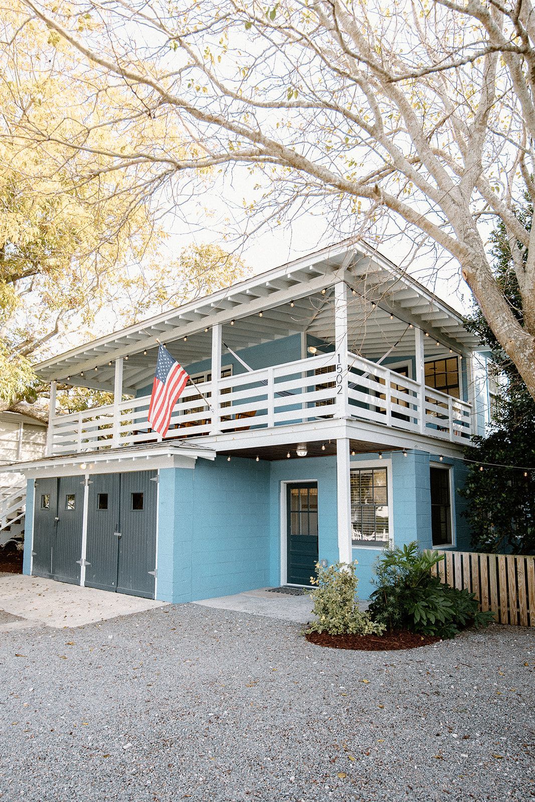 A blue house with a balcony and an american flag on it.