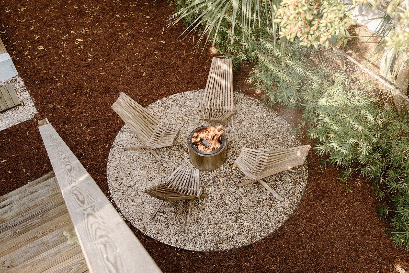 A fire pit with four chairs around it in a garden.