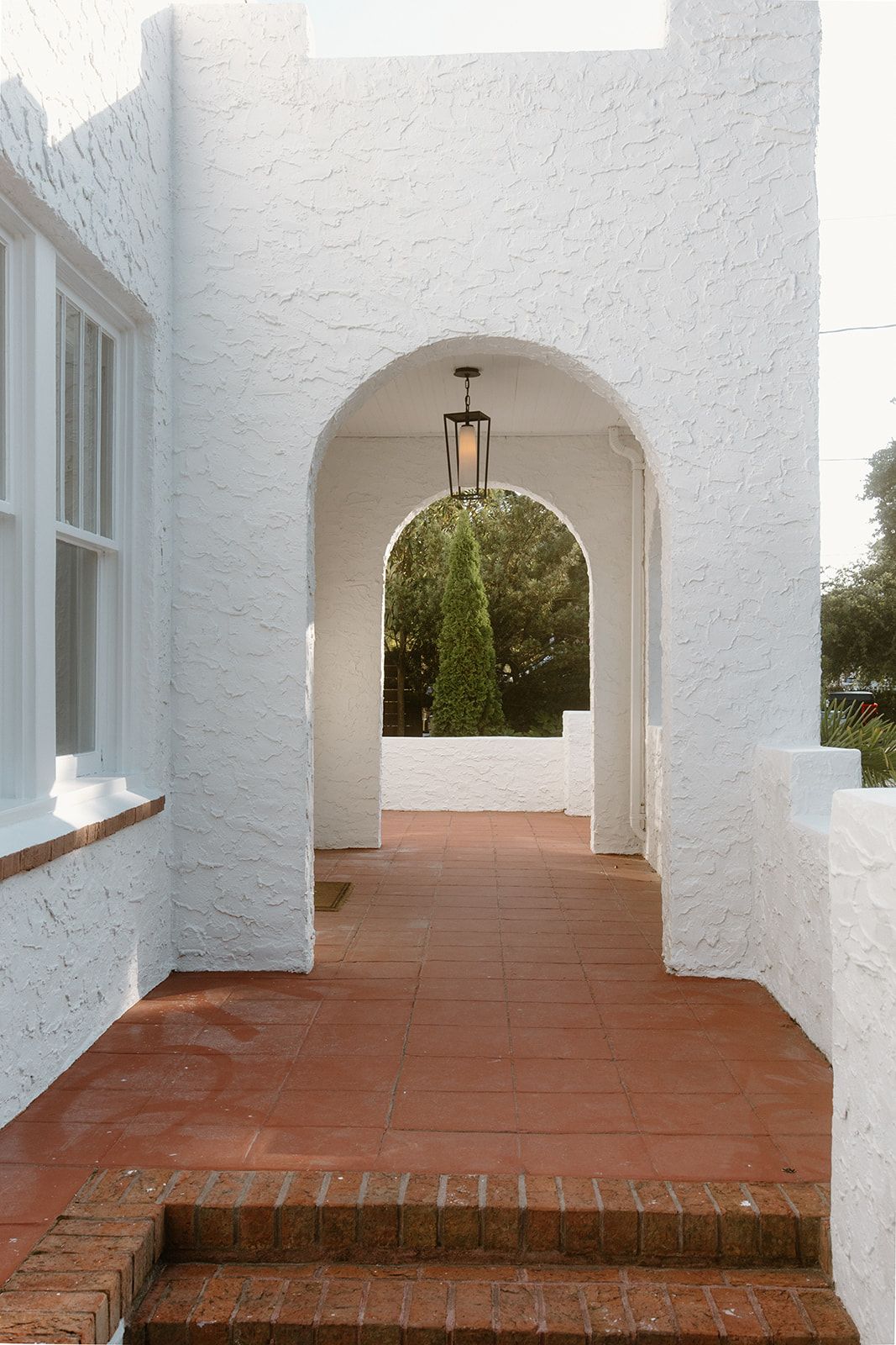 A white building with a red brick walkway leading to it.