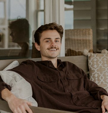 A man in a brown shirt is sitting on a couch