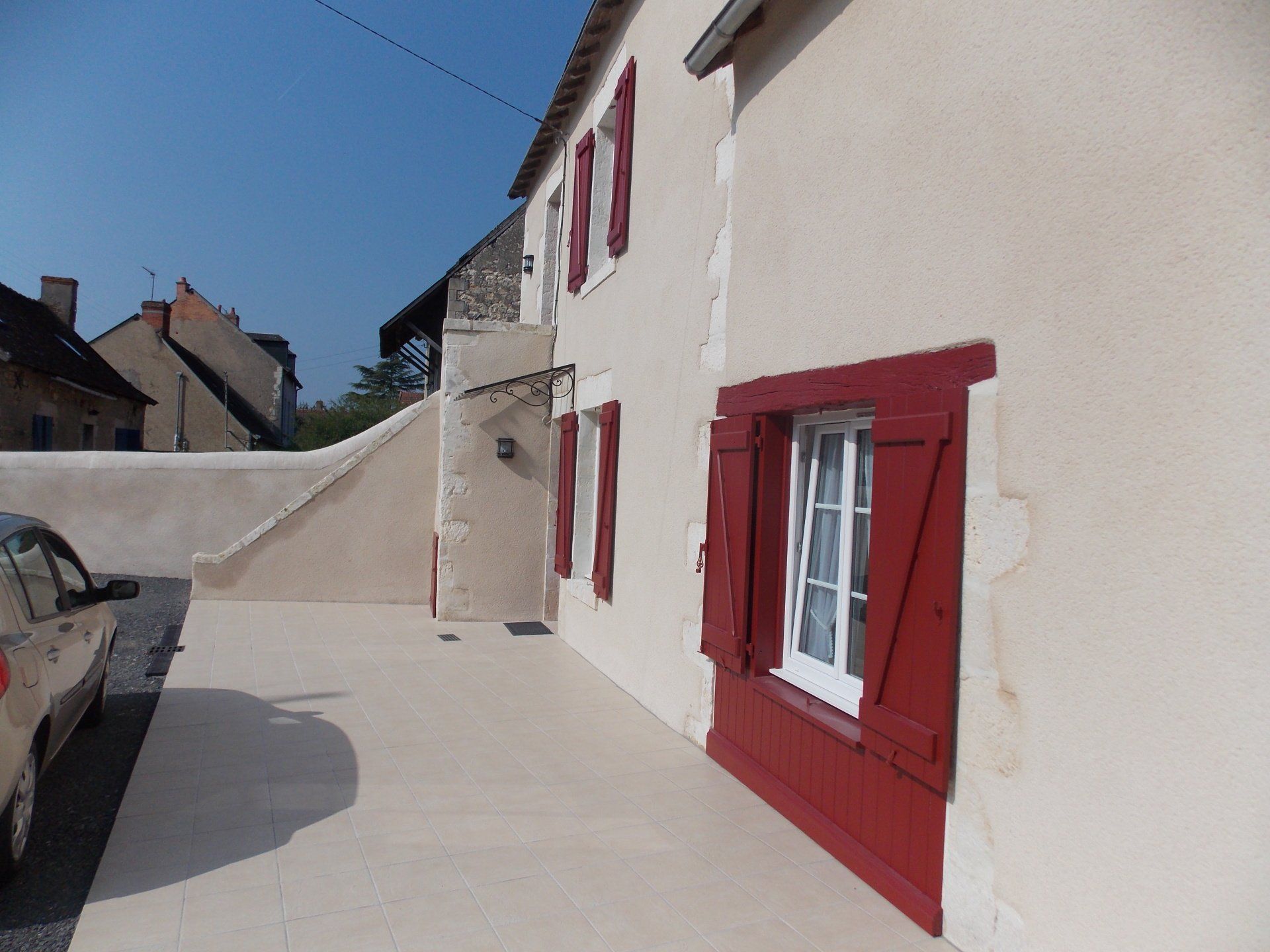 Maison à la façade blanche avec escalier extérieur et menuiseries peintes en rouge