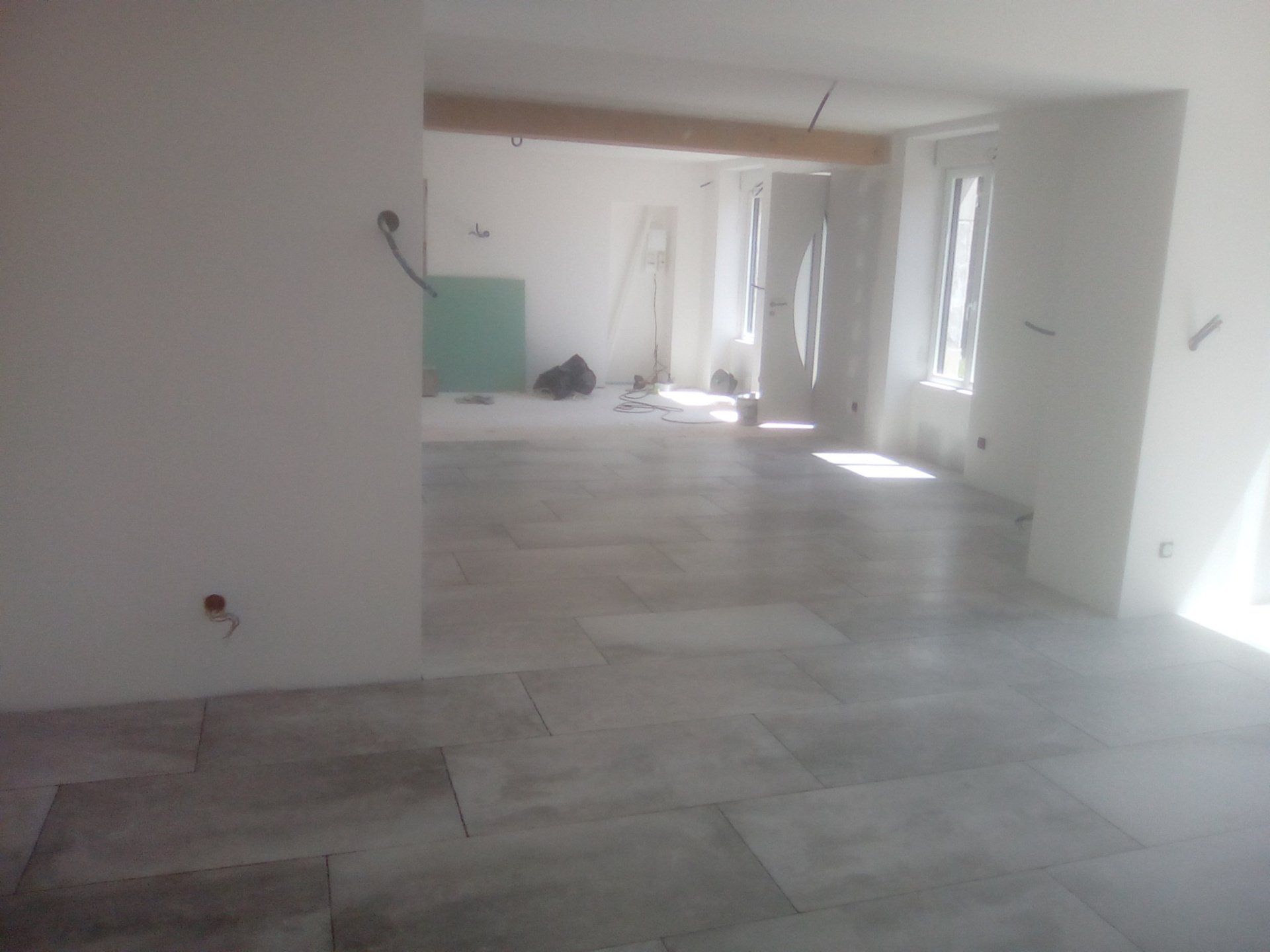 Pose de carrelage gris dans une maison neuve en construction