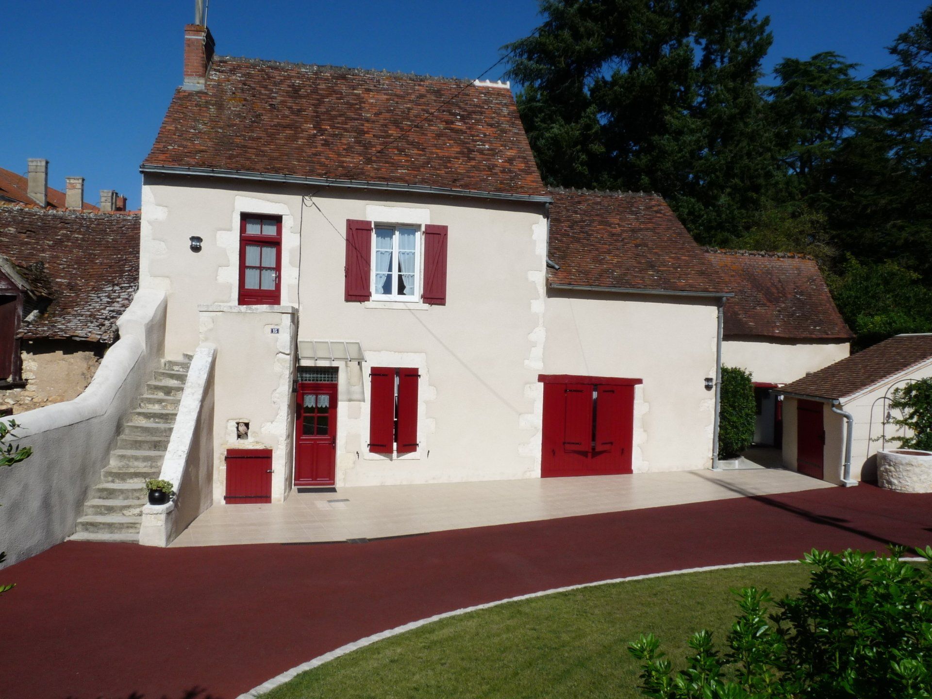 Maison à la façade blanche et aux menuiseries extérieures rouges
