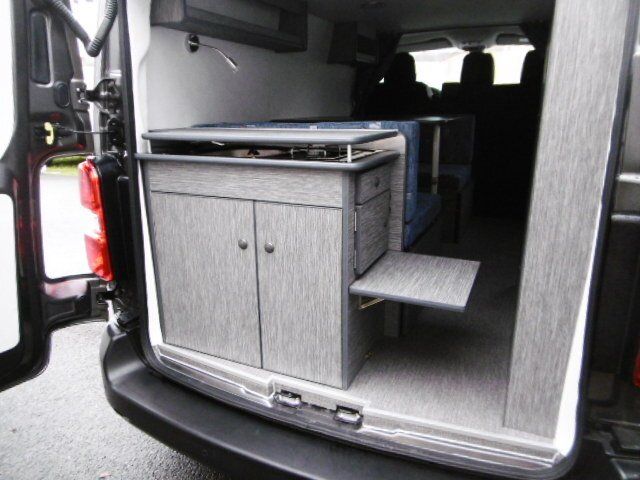 Petite cuisine à l'arrière d'un van avec une petite tablette relevée