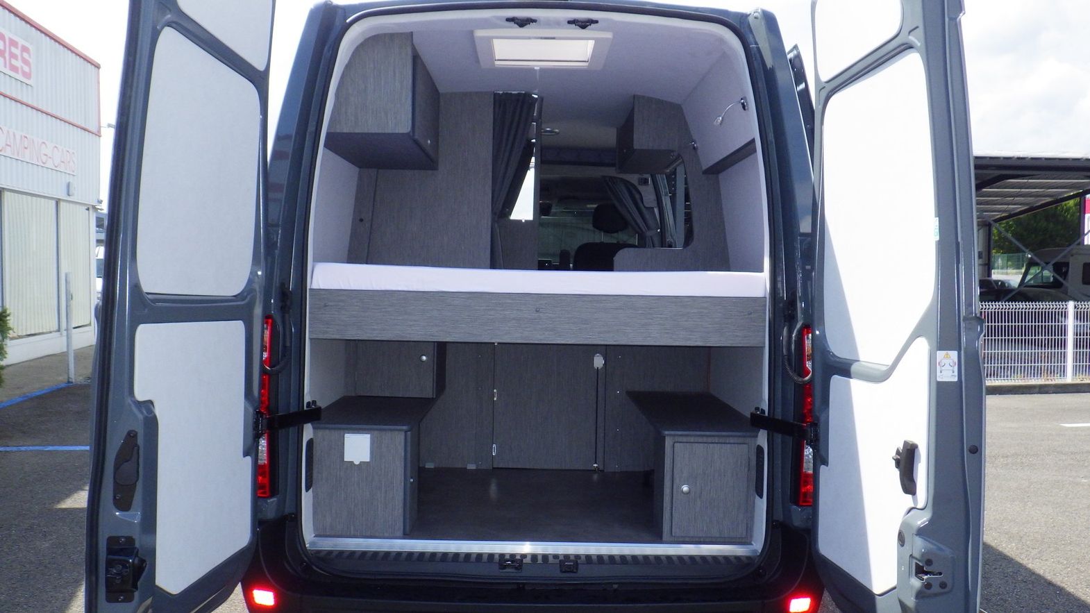 Lit installé dans un van vu par les portes arrières