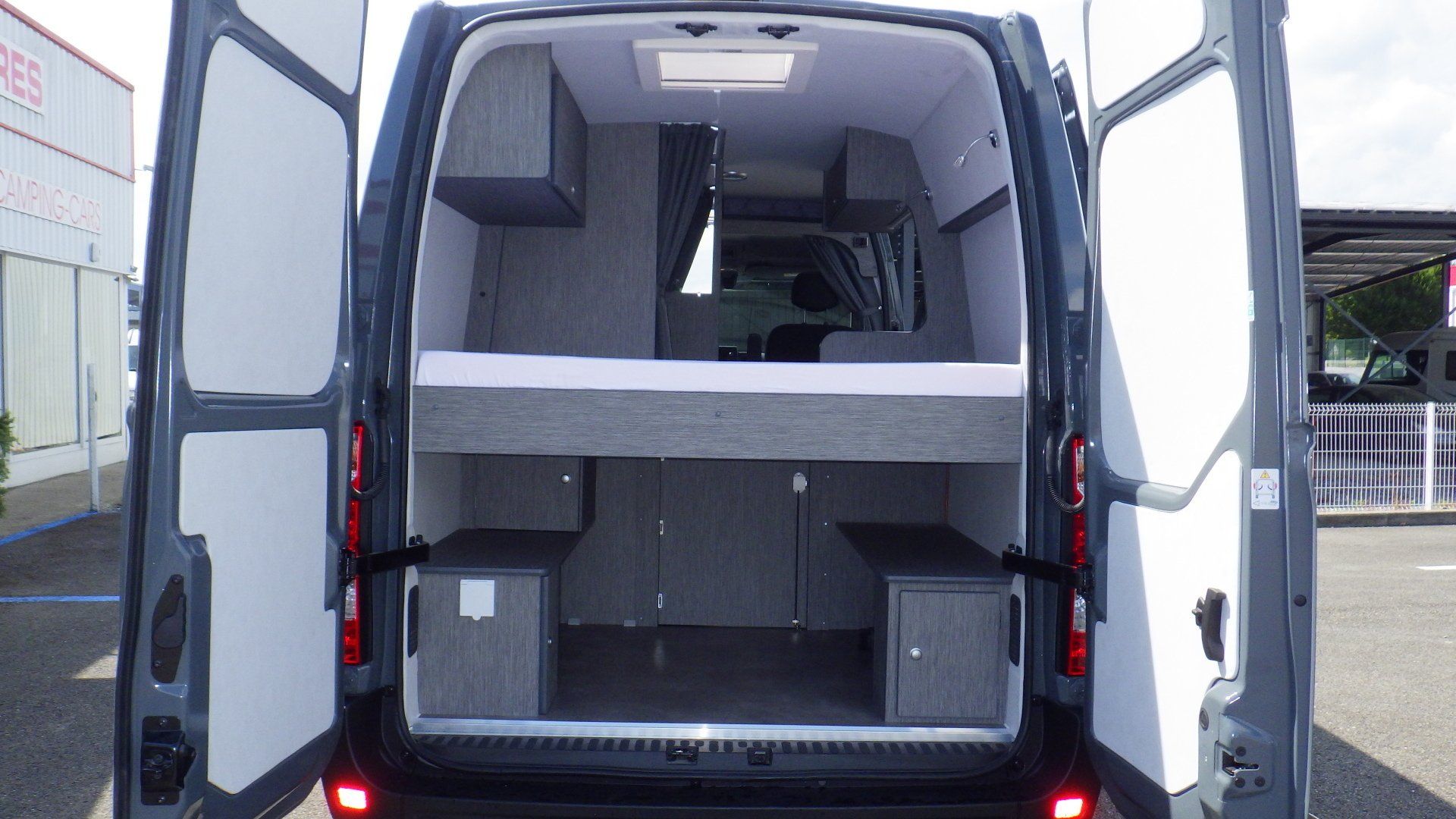 Lit installé dans un van vu par les portes arrières