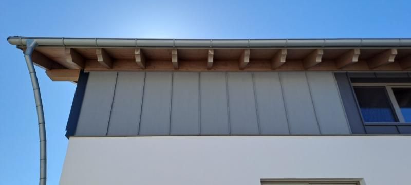 Eine moderne Hausfassade mit einer grauen, metallverkleideten oberen Wand
