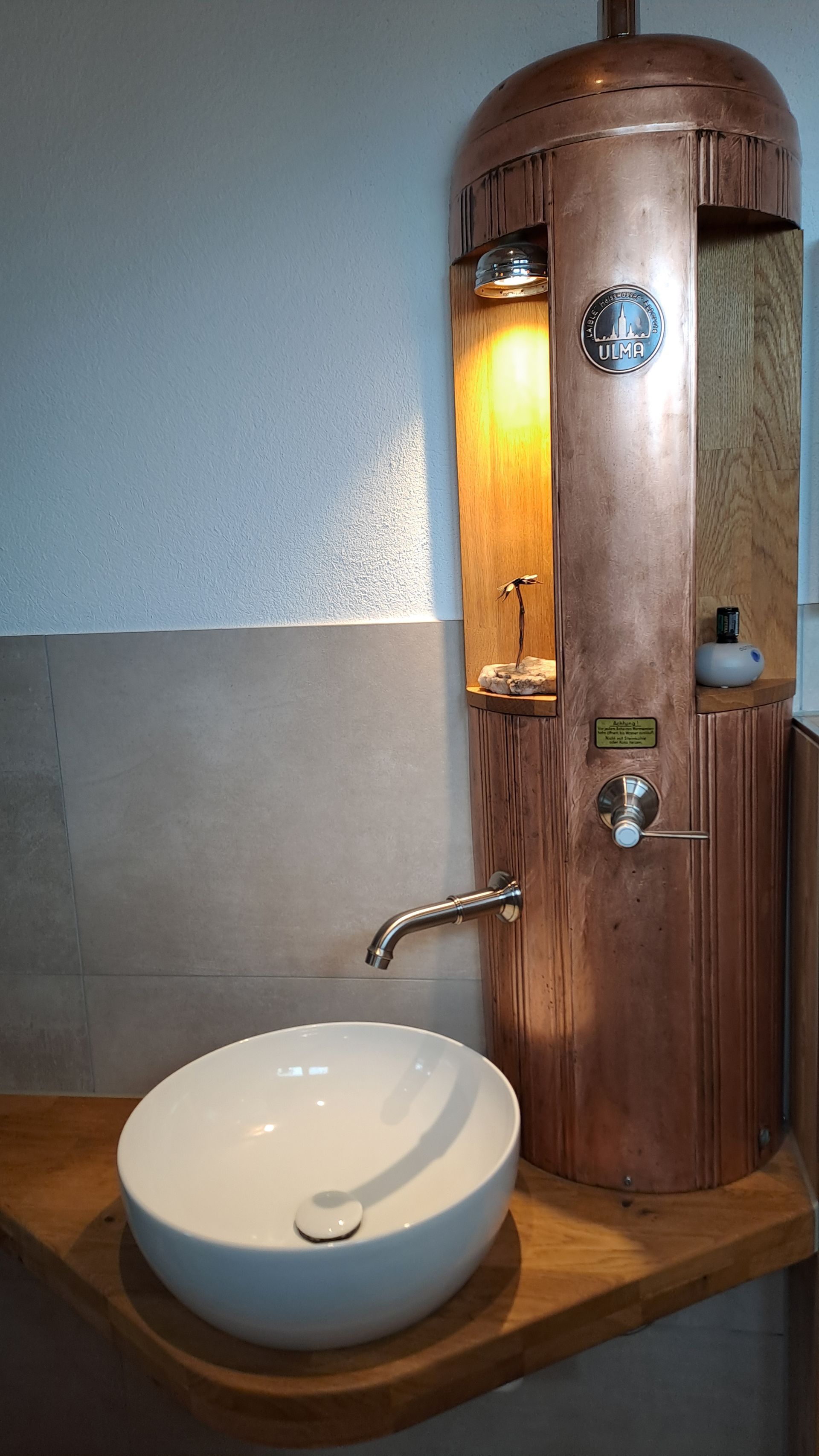 Holzwaschtischunterschrank mit rundem, weißem Becken und kleinem, an der Wand montiertem Wasserhahn.