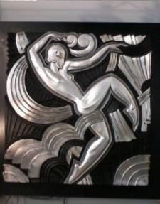 Relief abstrait en métal noir et argent représentant une figure stylisée en mouvement, aux formes courbes et amples.