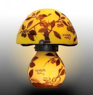 Lampe en forme de champignon à motif floral jaune, ornée de feuilles brunes et dotée d'un socle à la douce lueur.
