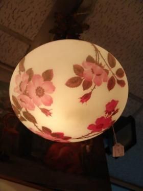 Plafonnier rond à motif floral avec des fleurs roses sur un abat-jour blanc, diffusant une lumière intérieure.