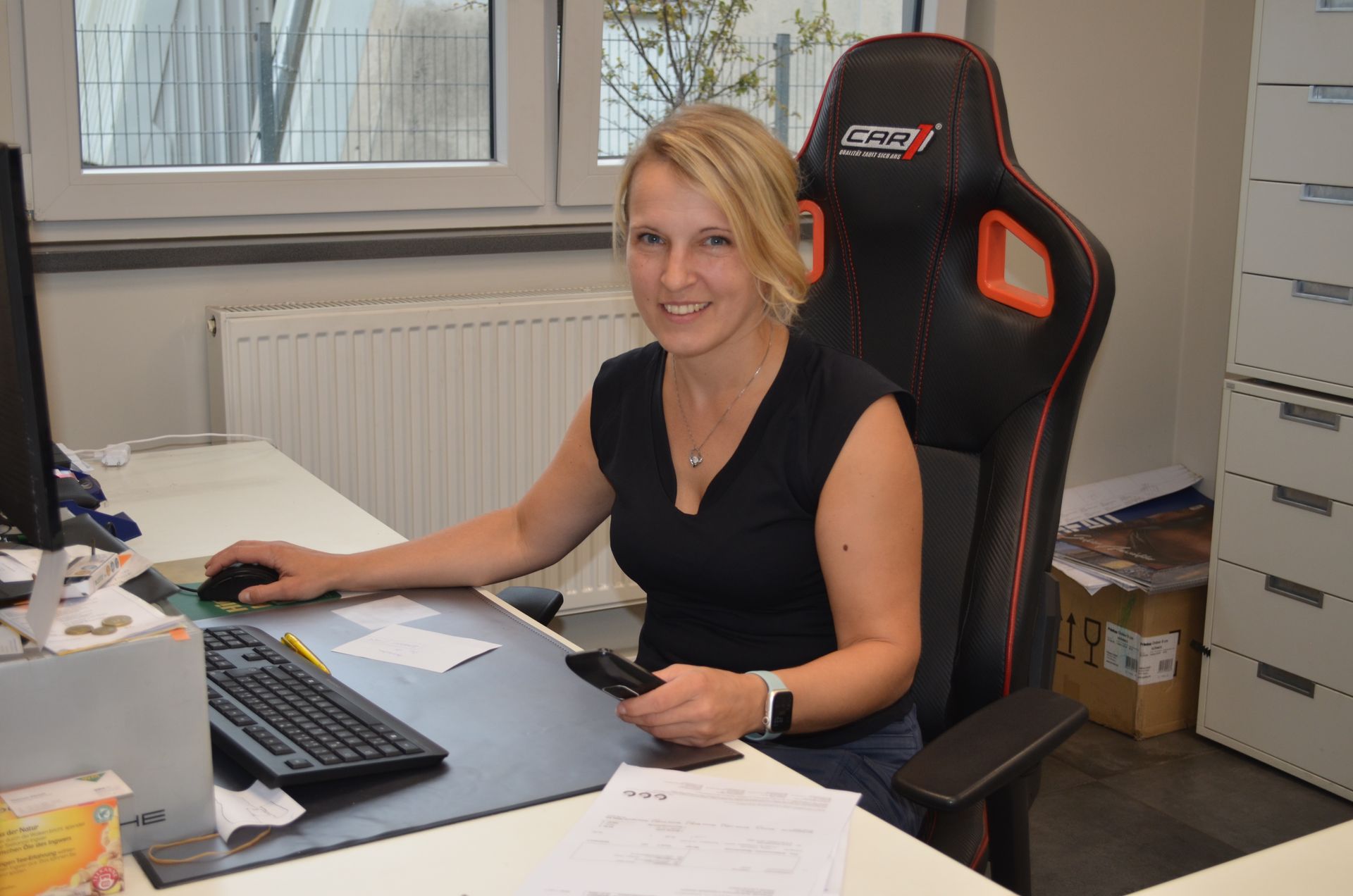 Eine Frau sitzt an einem Schreibtisch vor einem Computer.