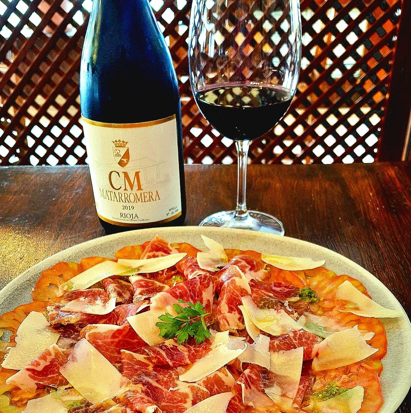 Una botella de vino cm se encuentra junto a un plato de comida.