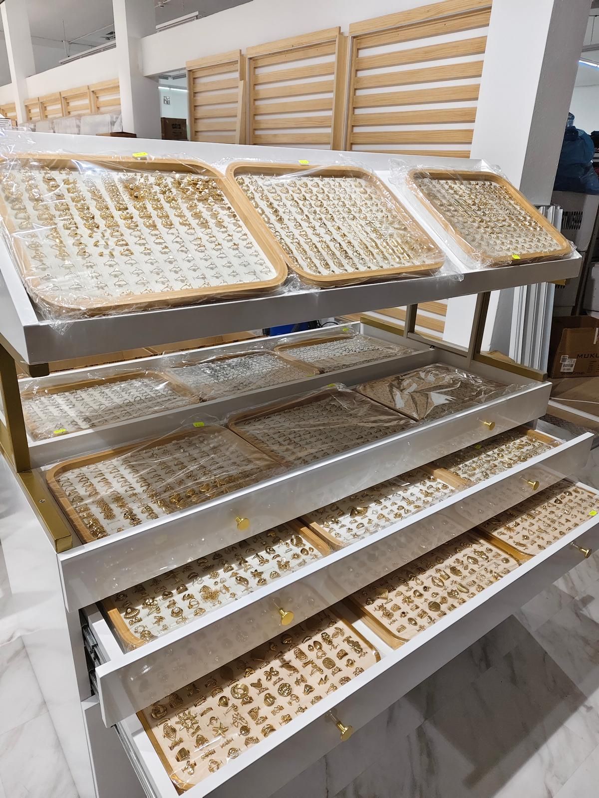 Expositor de joyas con múltiples bandejas para exhibir diversas piezas, para interior. Tonos blanco y tostado.