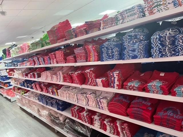 Estantes con camisetas rojas, blancas y azules dobladas en una tienda.