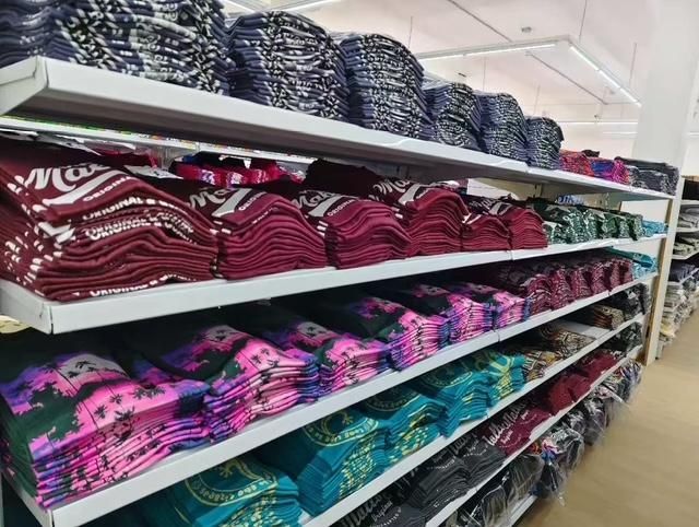 Estantes llenos de artículos textiles cuidadosamente doblados en varios colores: azul, rojo, morado y verde azulado, en una tienda.