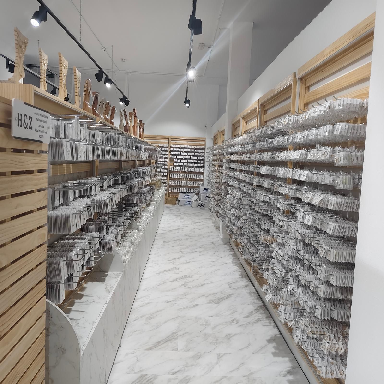 Pasillo largo de tienda lleno de estantes con productos envasados, iluminado con iluminación de riel.