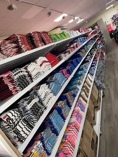 Estantes repletos de ropa cuidadosamente doblada en varios colores y patrones dentro de una tienda.