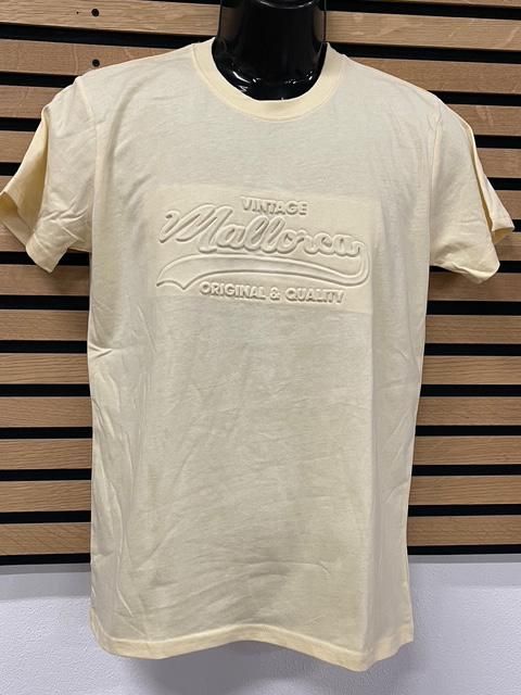 Camiseta de color amarillo claro con texto “Vintage Mallorca” en relieve en la parte delantera.