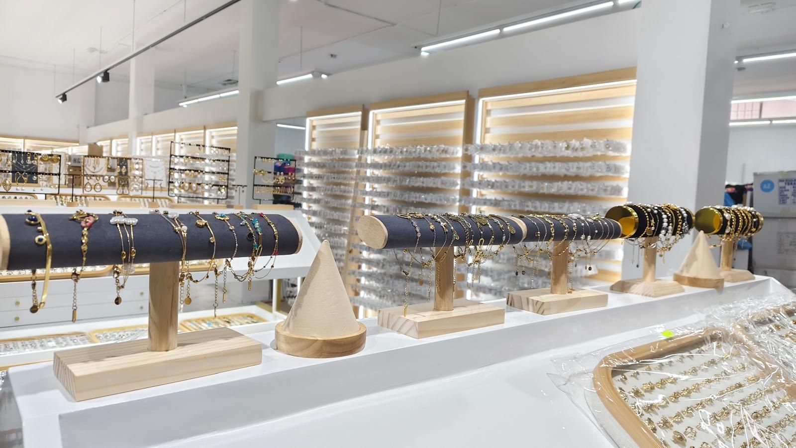 Exhibición de joyería con pulseras y aretes en soportes de madera. Interior bien iluminado.