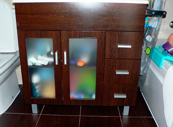 Un tocador de baño con puerta de vidrio y cajones.