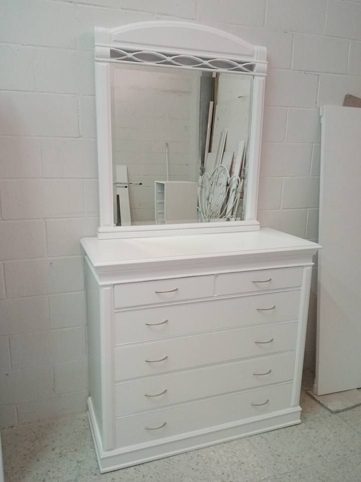 Una cómoda blanca con un espejo encima en una habitación.