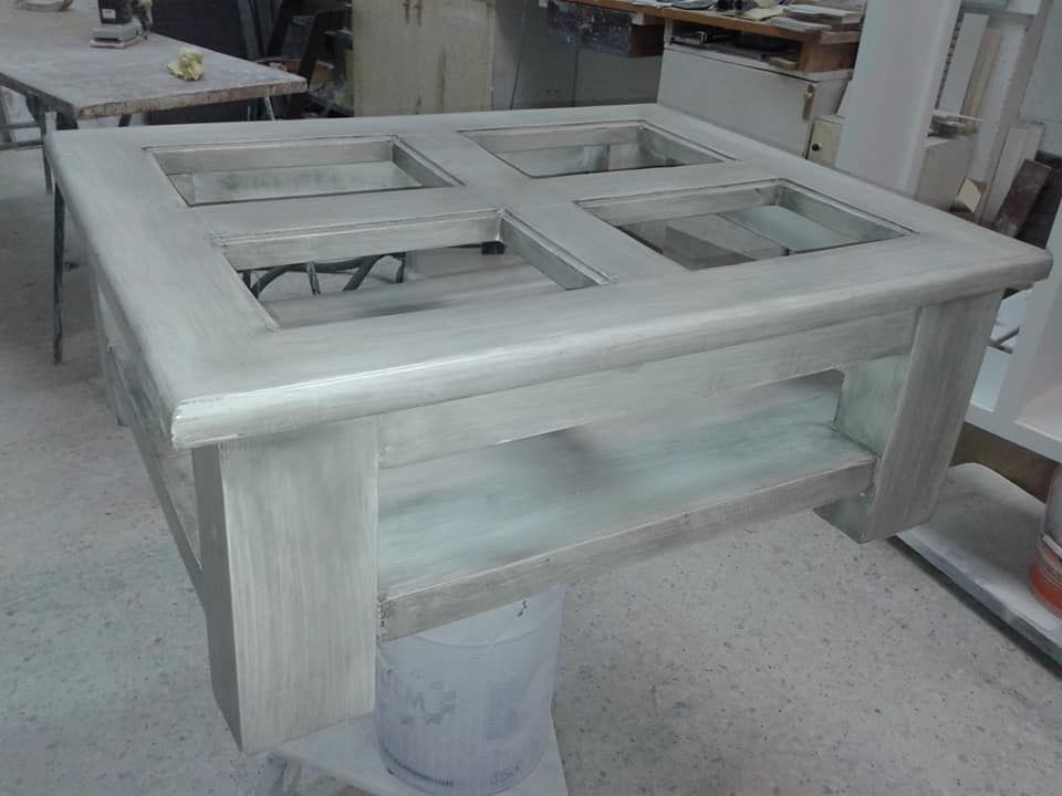 Se está pintando una mesa de madera con tapa de cristal en una habitación.
