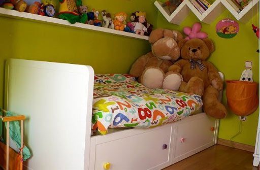 Dos osos de peluche están sentados en una cama en la habitación de un niño.