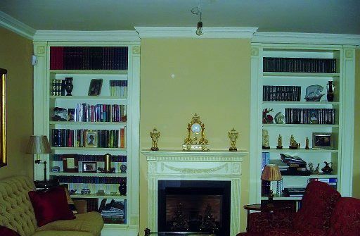 Una sala de estar con chimenea y estanterías llenas de libros.