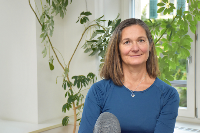 Eine Frau in einem blauen Hemd sitzt vor einem Fenster.