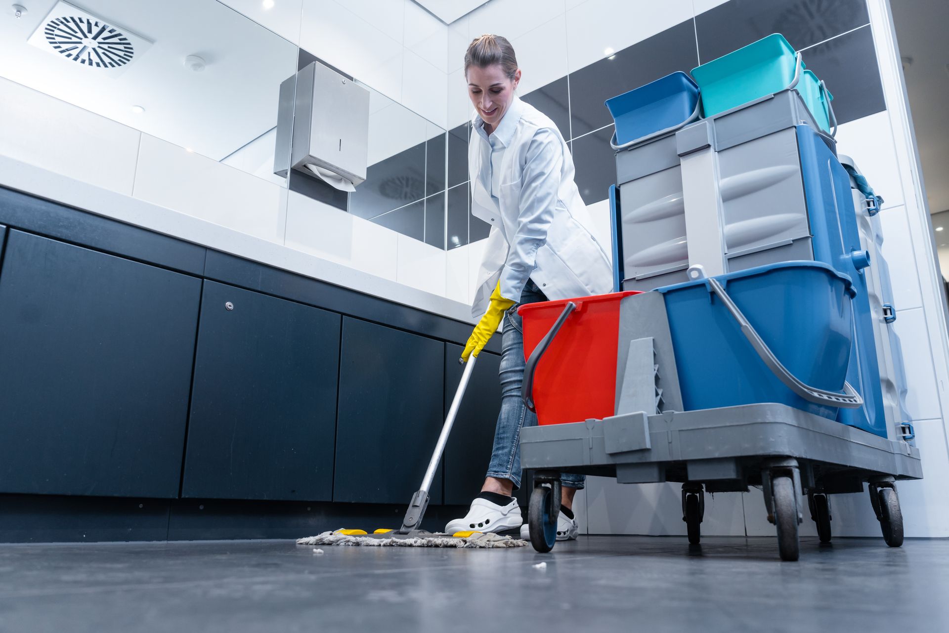 Femme de ménage passant la serpillière dans les toilettes