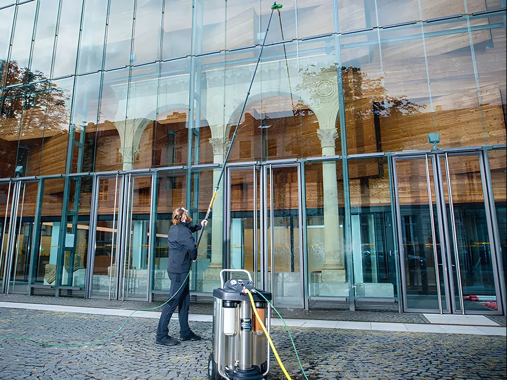 Homme qui nettoie les vitres d'un bâtiment avec une machine H2O