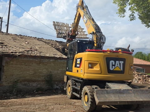 Une pelle jaune qui démolit une maison