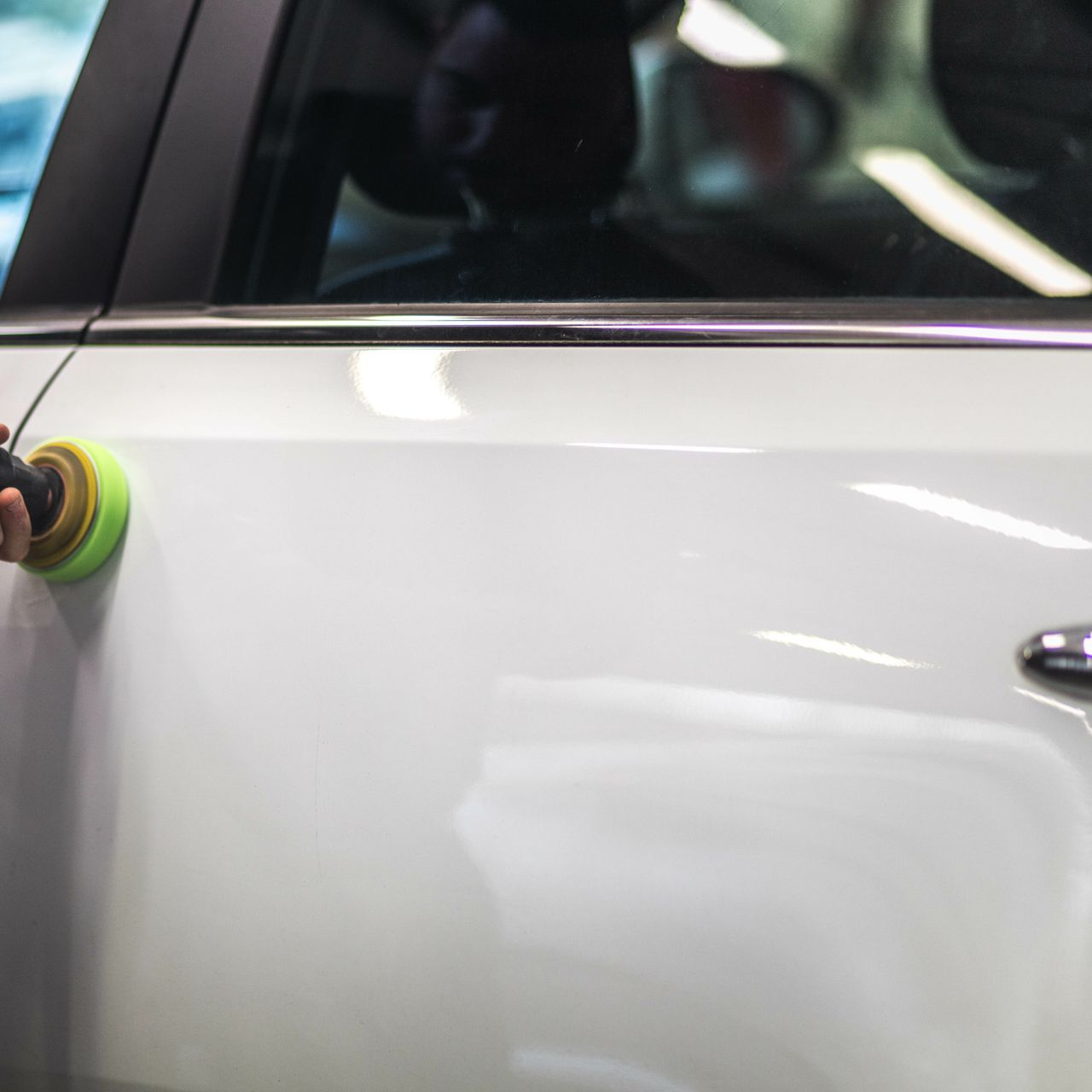 Gros plan sur une portière de voiture blanche polie avec une polisseuse