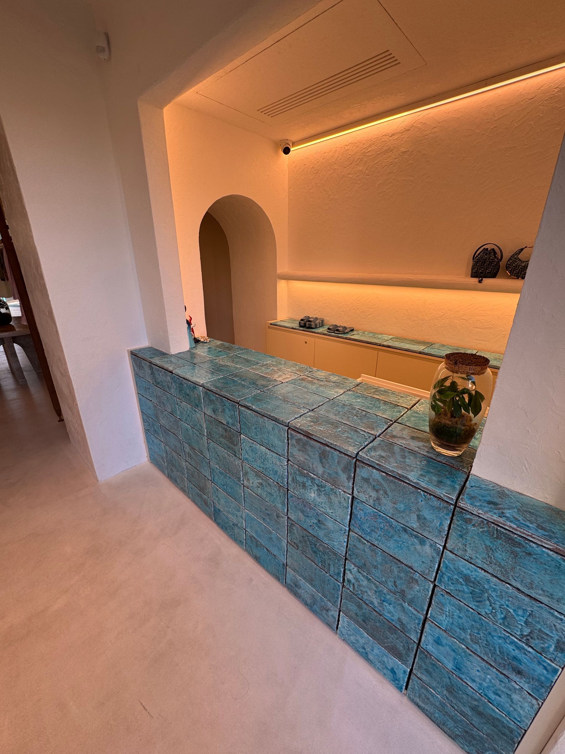 Un comptoir texturé turquoise dans une pièce lumineuse avec une porte cintrée.