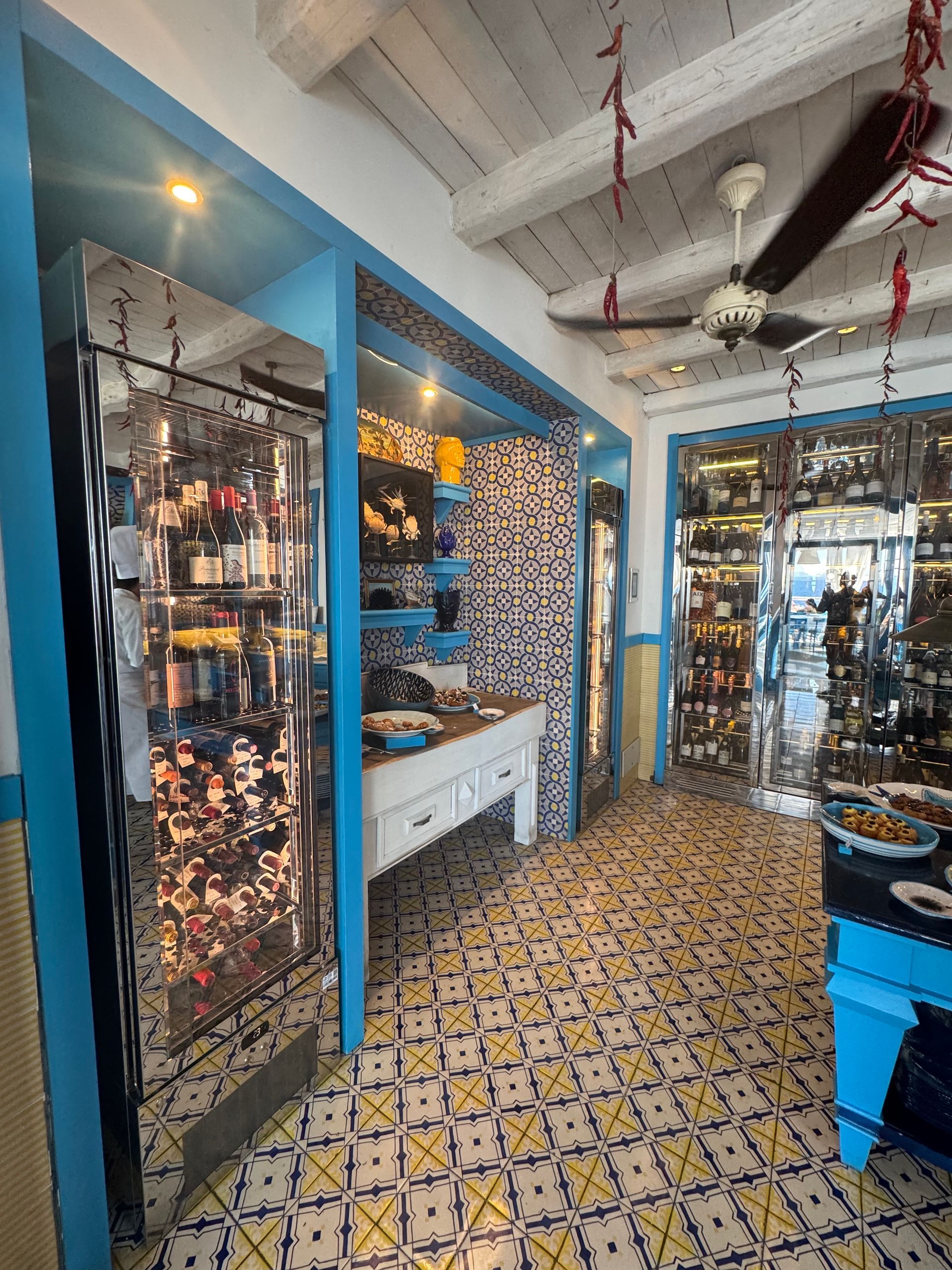 Pièce étroite avec des carreaux muraux géométriques dorés et noirs et des murs latéraux en marbre, éclairée par un éclairage zénithal.