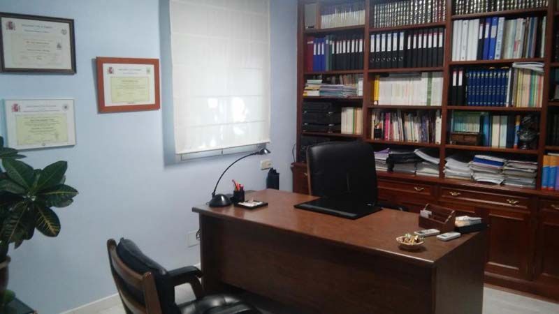 Un escritorio con una computadora encima en una habitación con estanterías.