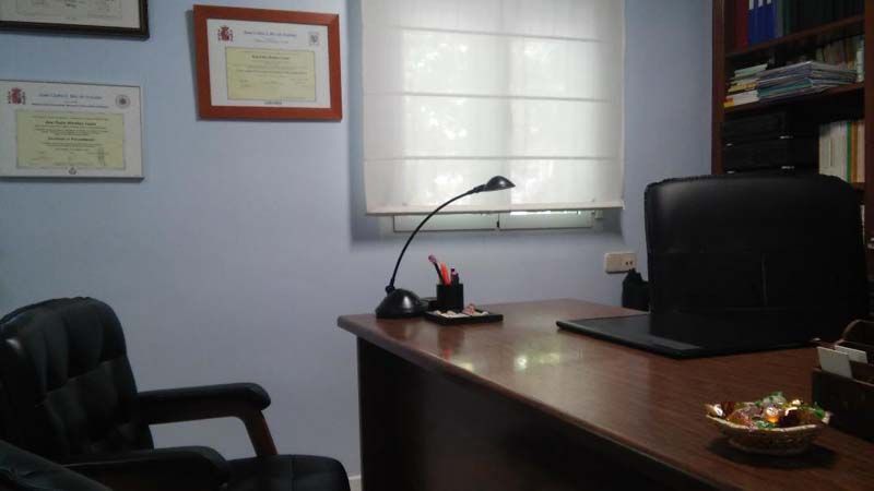 Una habitación con un escritorio, una silla, una lámpara y una ventana.