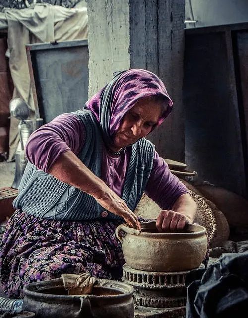 Una mujer que lleva un pañuelo en la cabeza está trabajando en una olla.