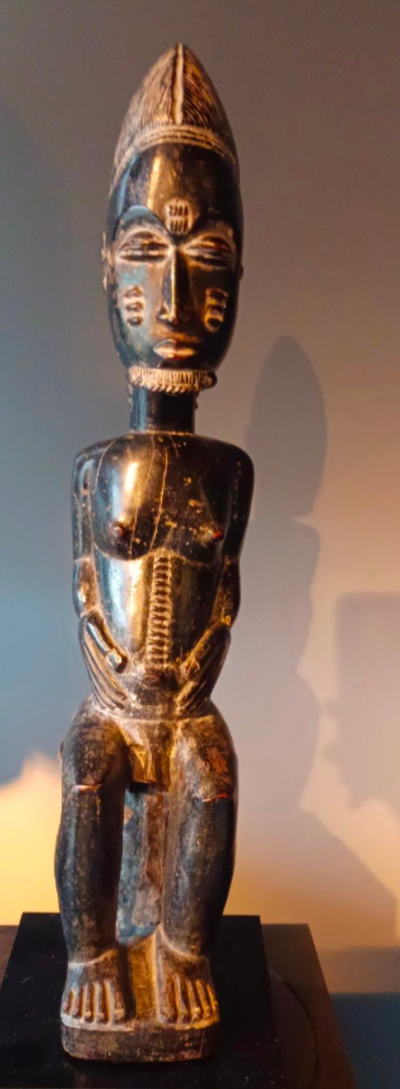 Statuette d'une personne assise avec un chapeau pointu