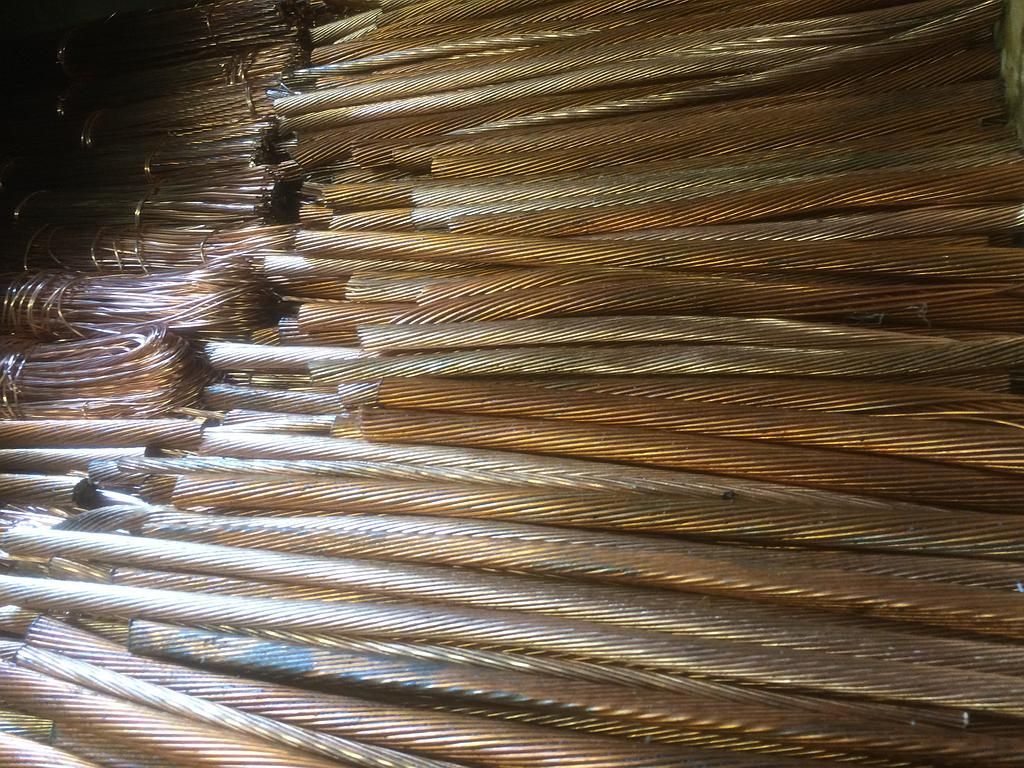 Un tas de fils de cuivre, de textures et d'épaisseurs variées, dans un environnement sombre, possiblement industriel.
