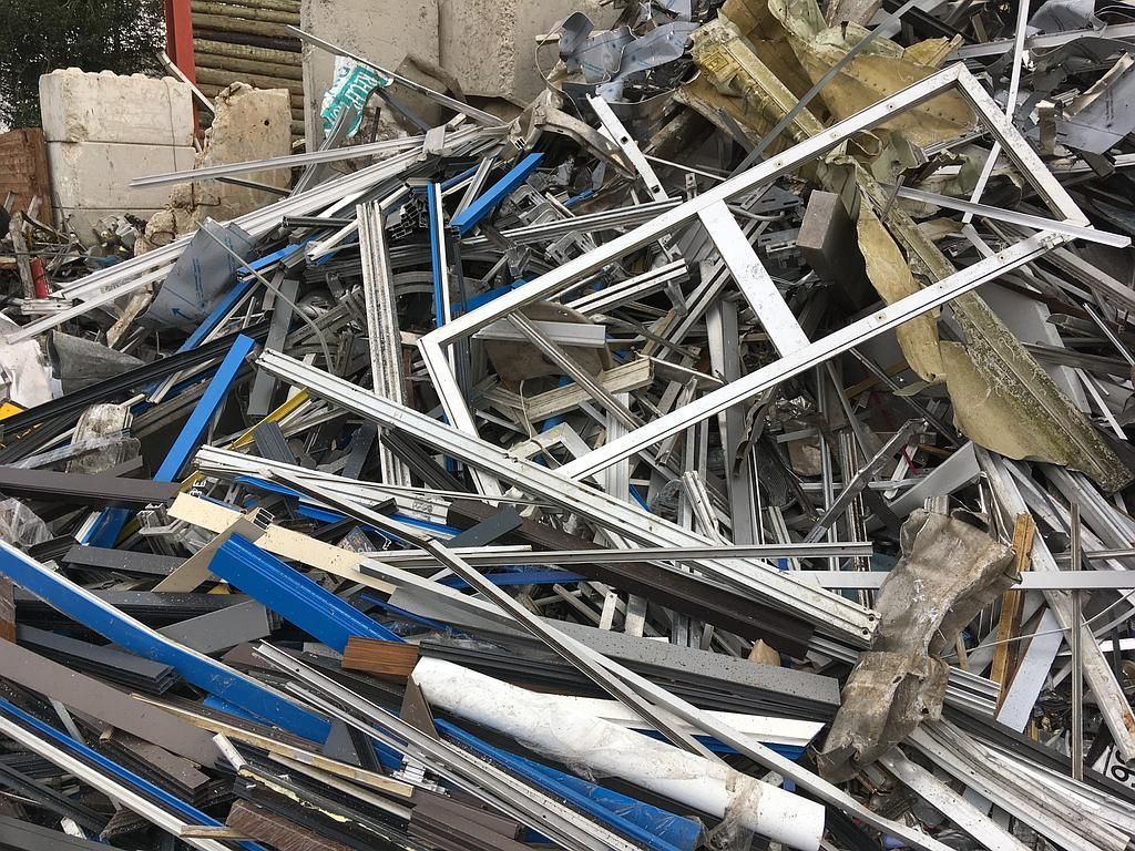 Un tas de ferraille, comprenant une fenêtre à cadre blanc et des bandes de métal bleues.