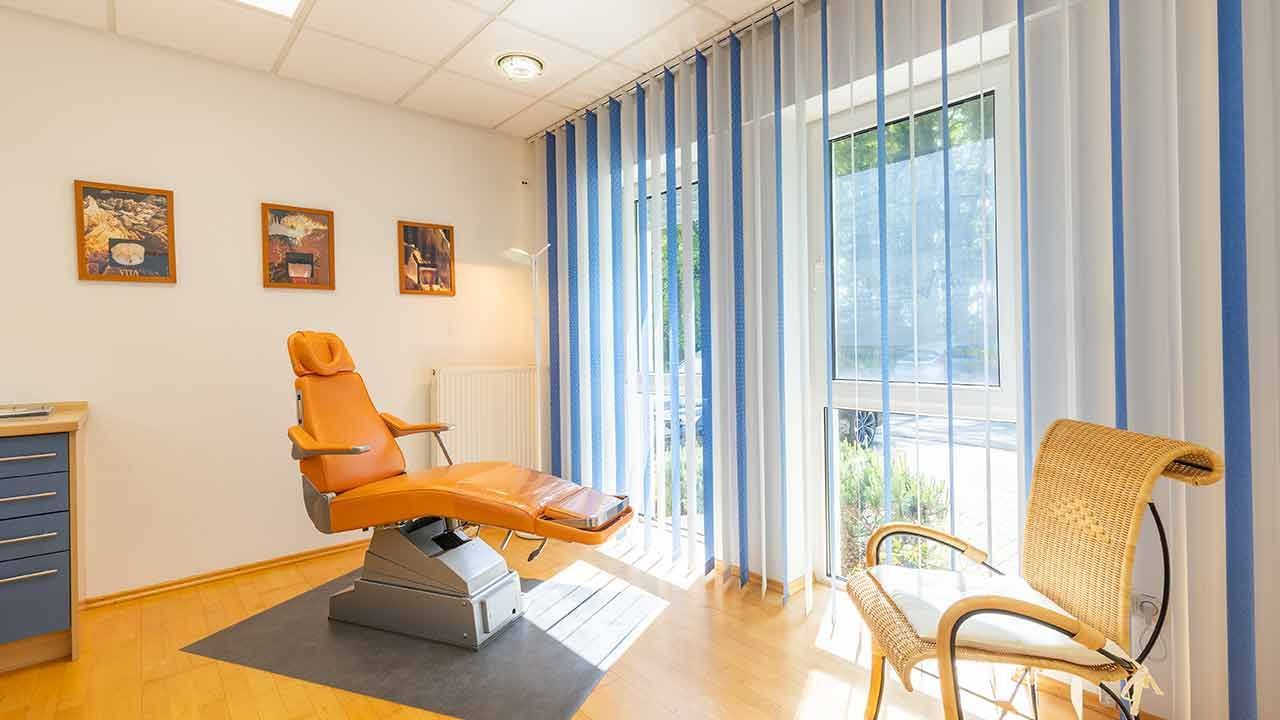Ein Raum mit einem Stuhl und einem Fenster mit blauen und weißen Vertikaljalousien.