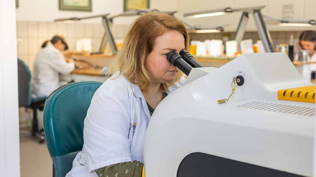 Eine Frau schaut in einem Labor durch ein Mikroskop.