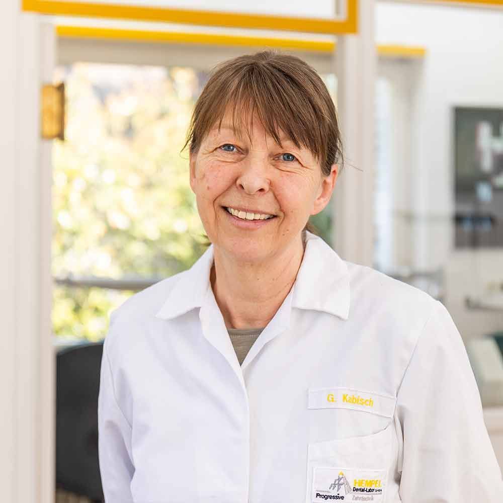 Eine Frau im weißen Laborkittel lächelt in die Kamera.