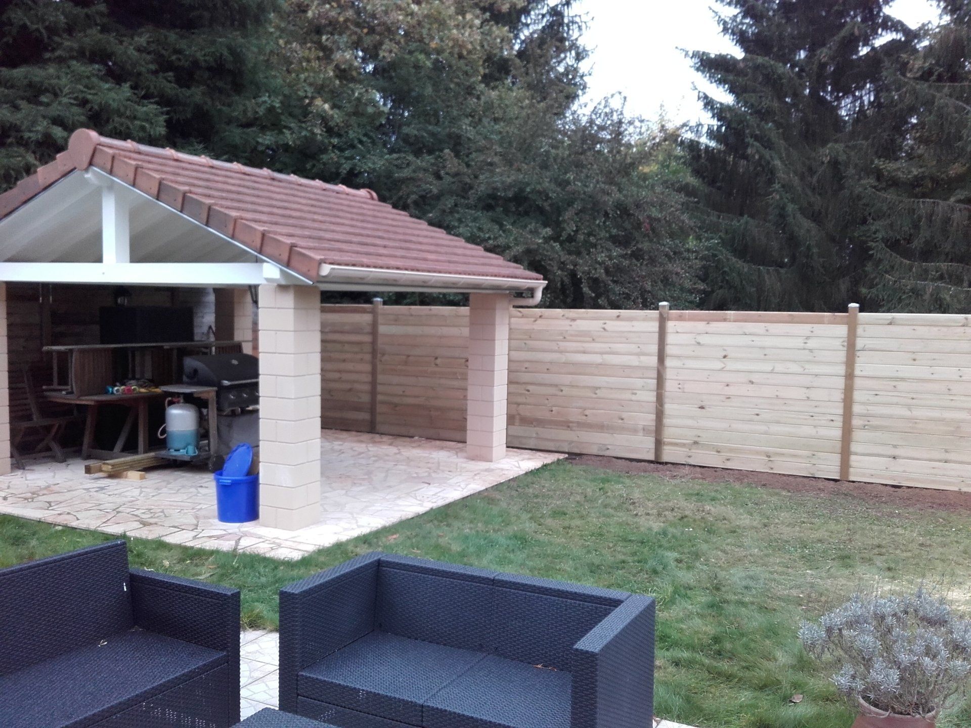 Terrasse en bois avec clôture et salon extérieur.