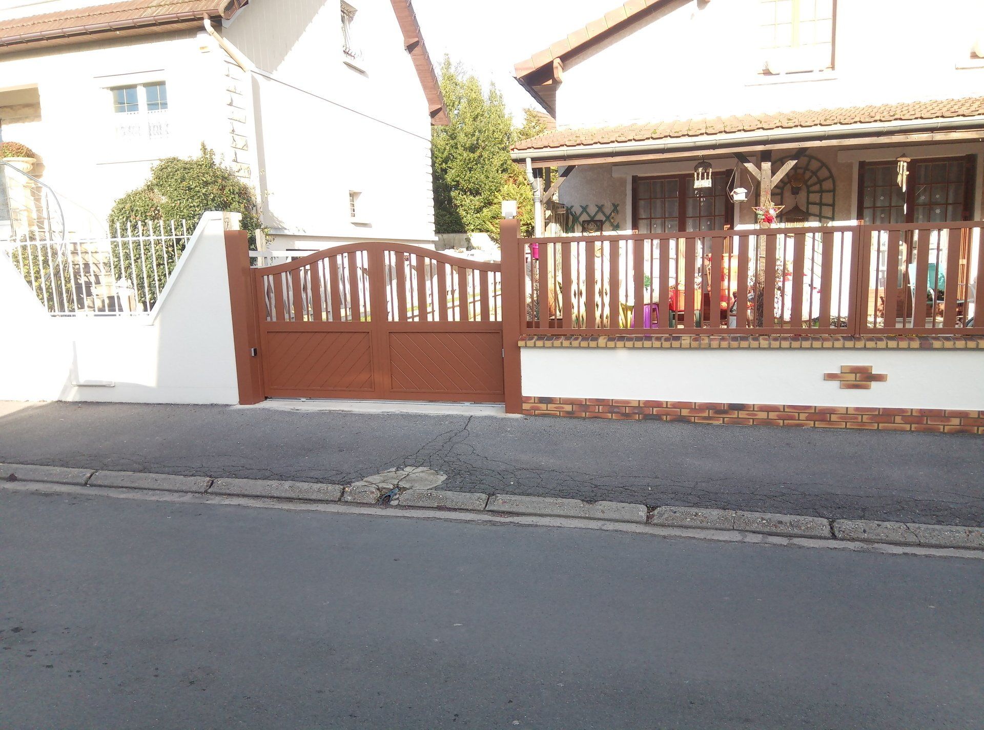 Portail et clôture marron devant une maison dans une rue.